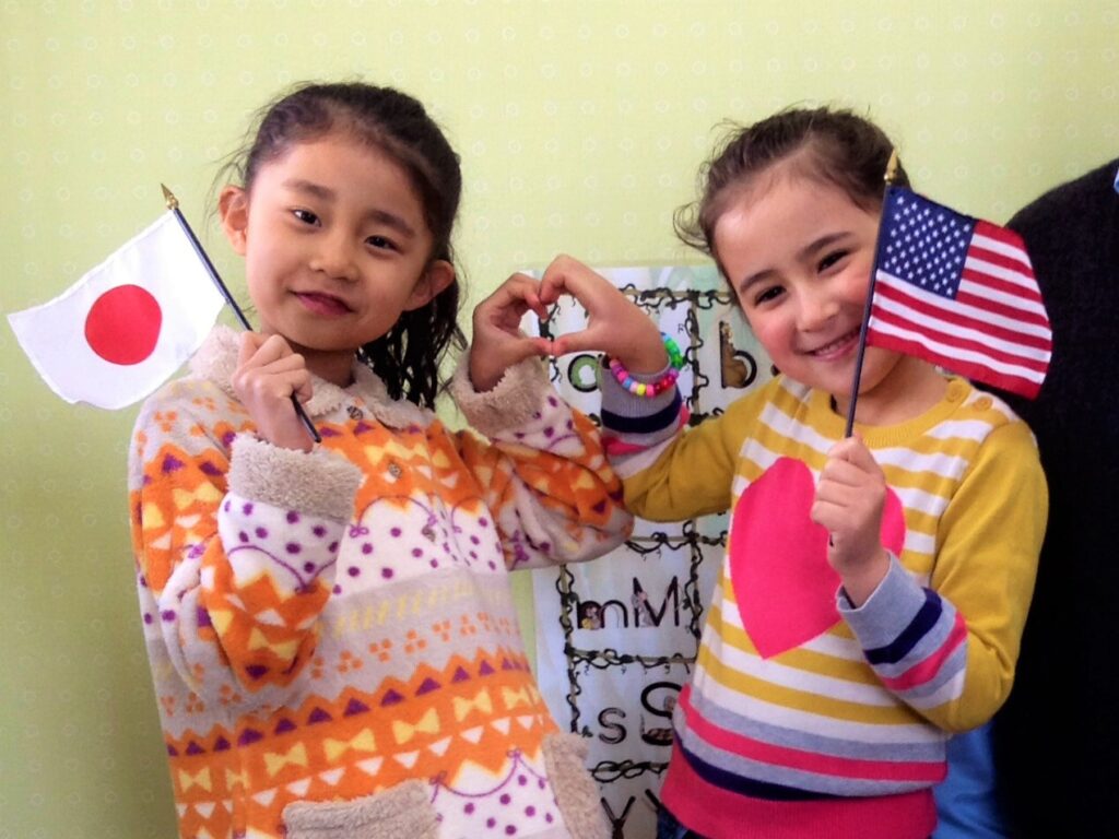 国旗を持つ日本人の女の子とアメリカ人の女の子